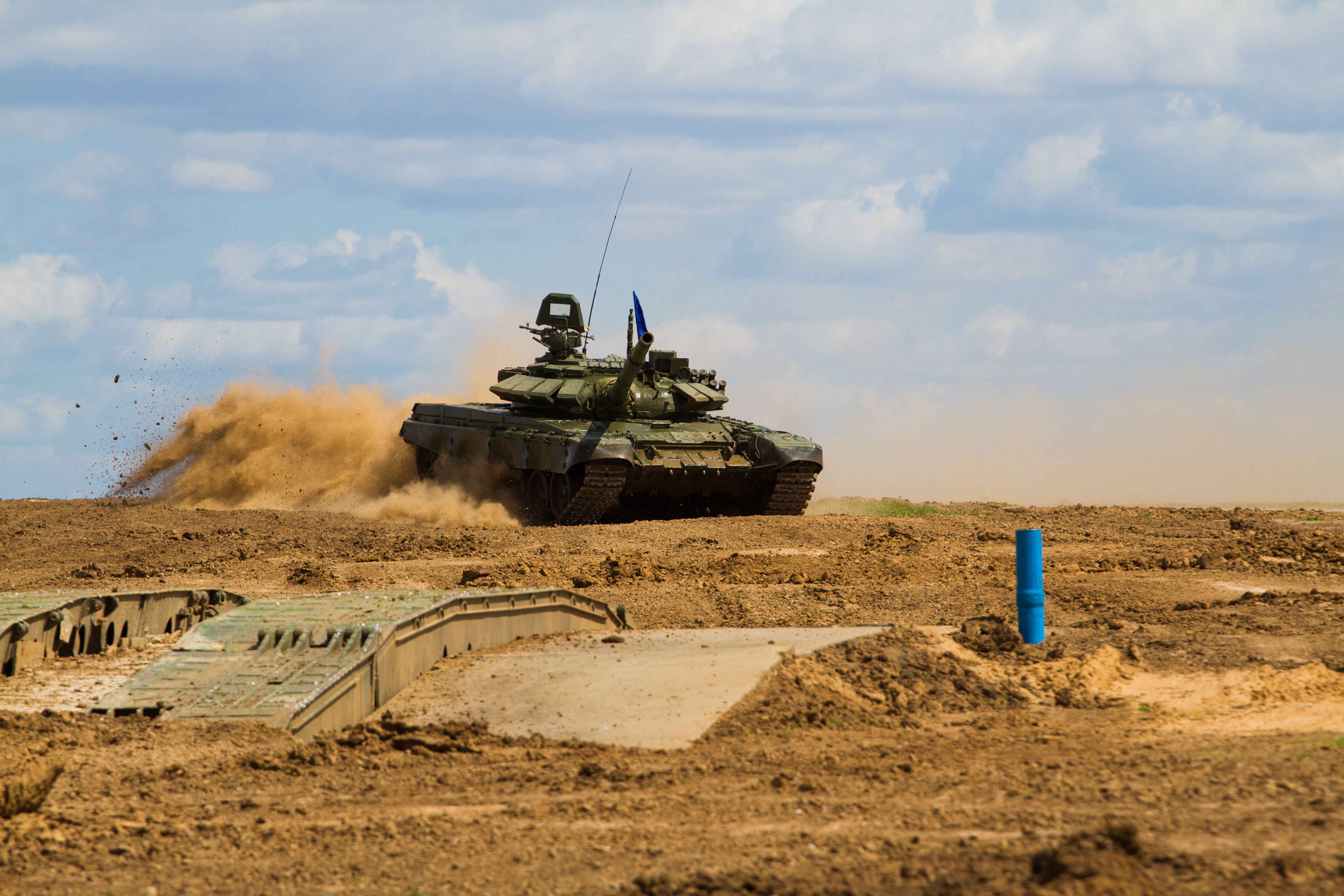 KJ Reports, Europe — A column of modern K2 Black Panther tanks moving through a Polish training ground during a sunset, symbolising the new military weight o…