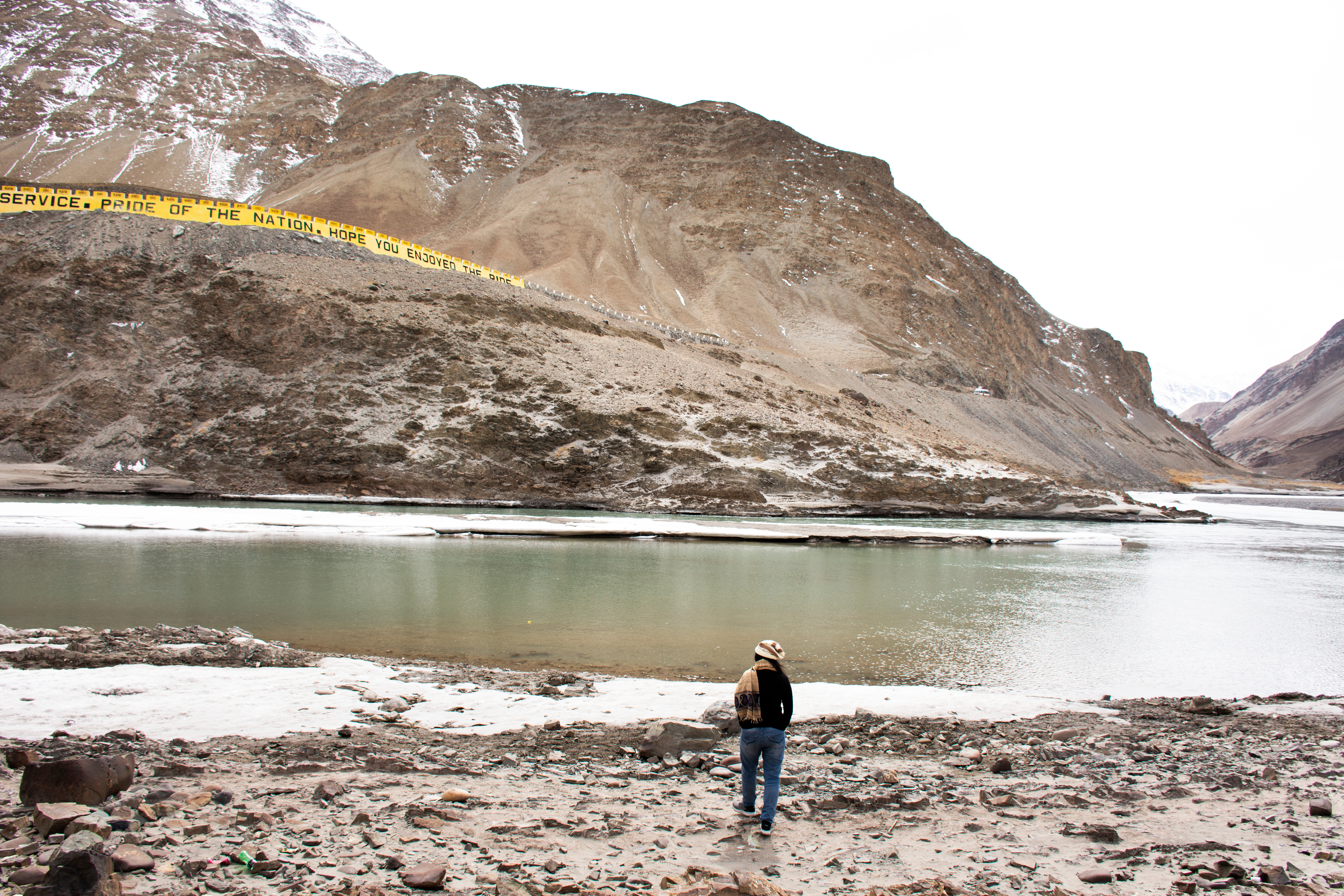 KJ Reports, South Asia — A wide, cinematic shot of a massive concrete hydroelectric dam nestled in the steep, rocky valleys of the Himalayan mountains under…