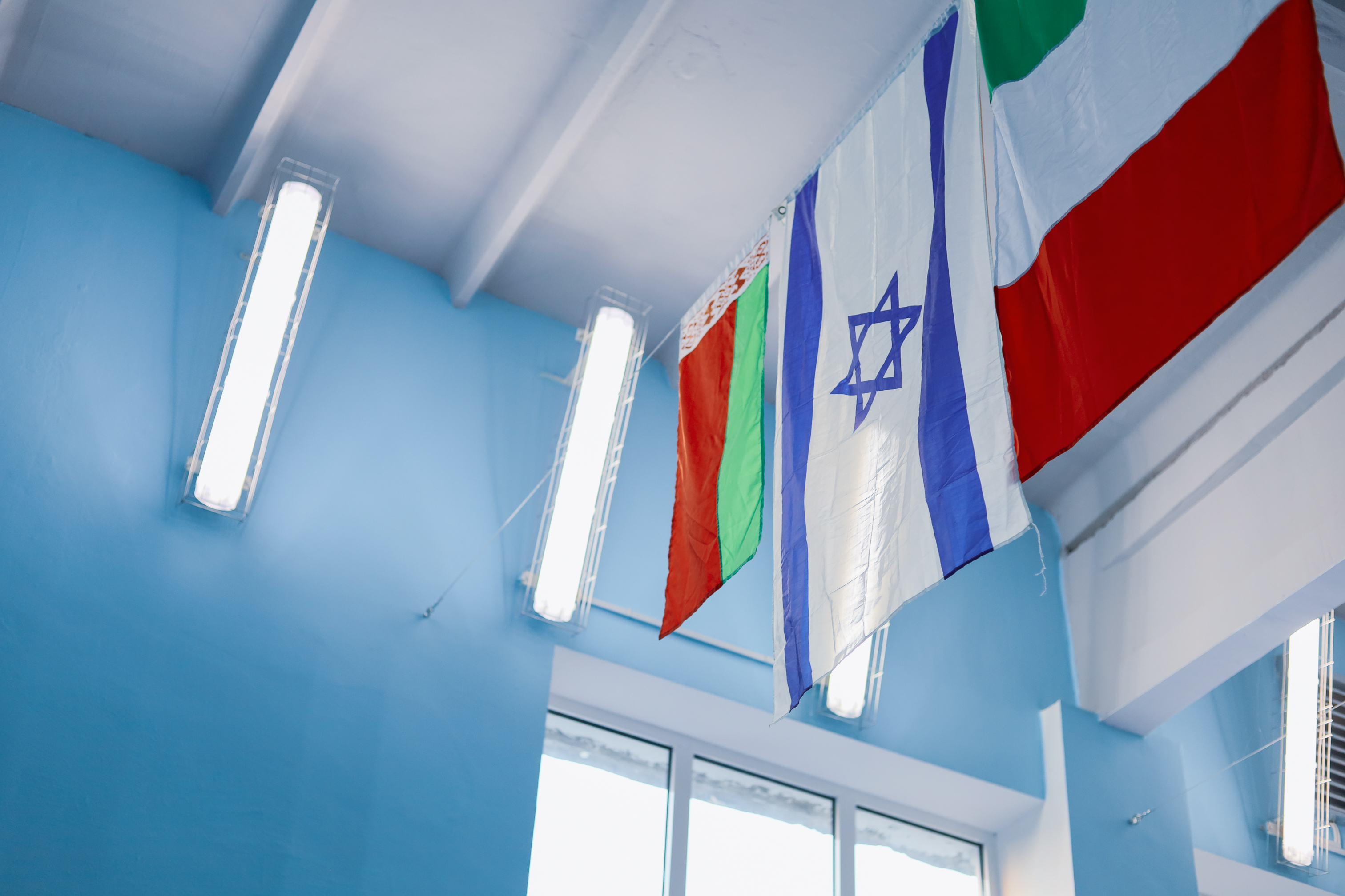 KJ Reports, Global — A wide-angle, cinematic shot of a geopolitical map of the Middle East spread across a dark wooden table, with national flags of the US,…